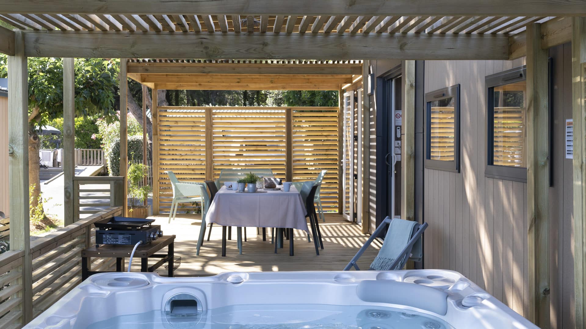 Terrasse bois avec jacuzzi et table dressée.